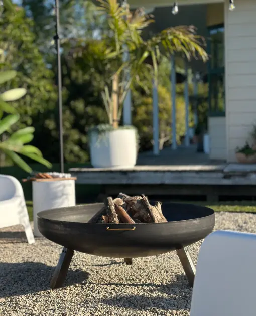 Fire bowl on a gravel courtyard beside a planted pot
