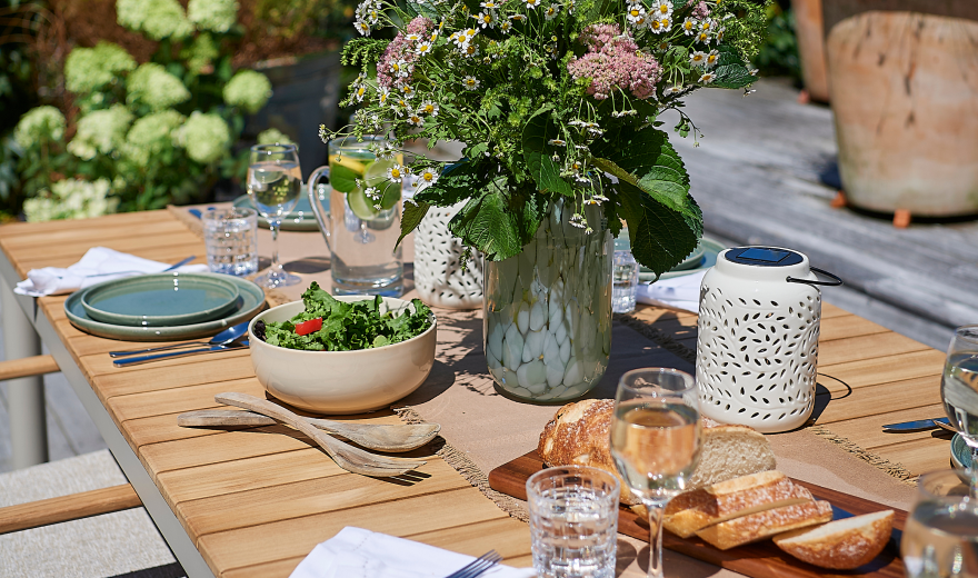 Outdoor cushions, a lantern and tableware arranged on a table