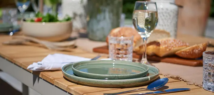 Outdoor table set with plates, glasses and shared food