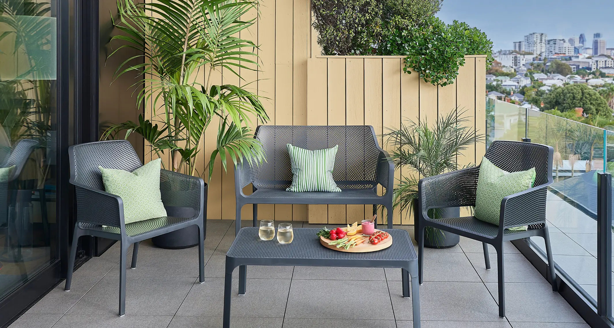 Compact outdoor lounge setting on a balcony with planters and a clear walkway